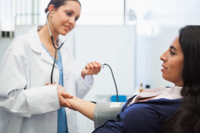 Doctor measuring the blood pressure of a Latina patient